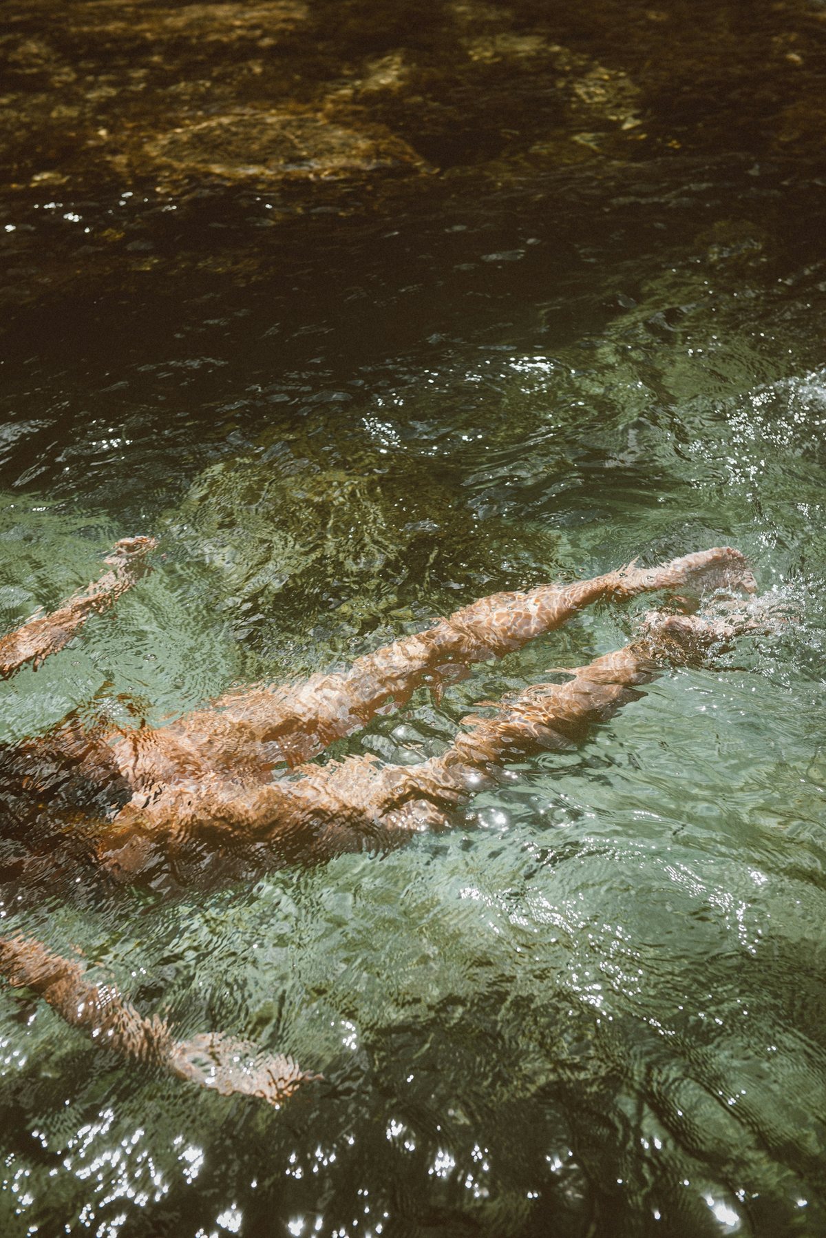 A woman swimming through clear green water