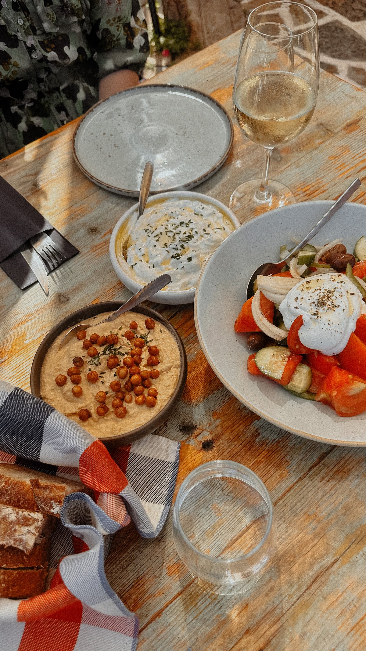 A shared table with salad, dips, and bread in warm light