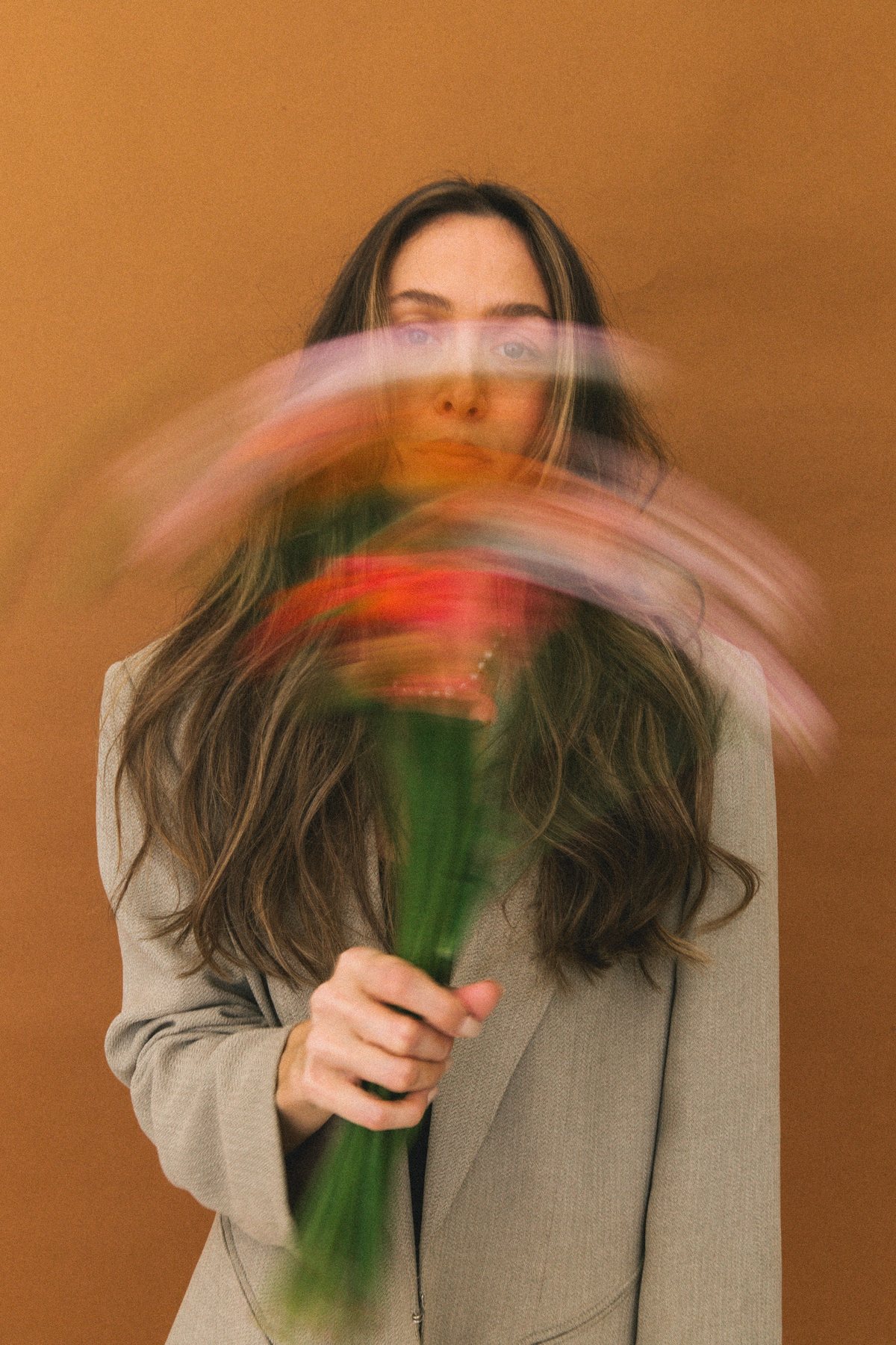 A woman holding motion-blurred flowers before her face